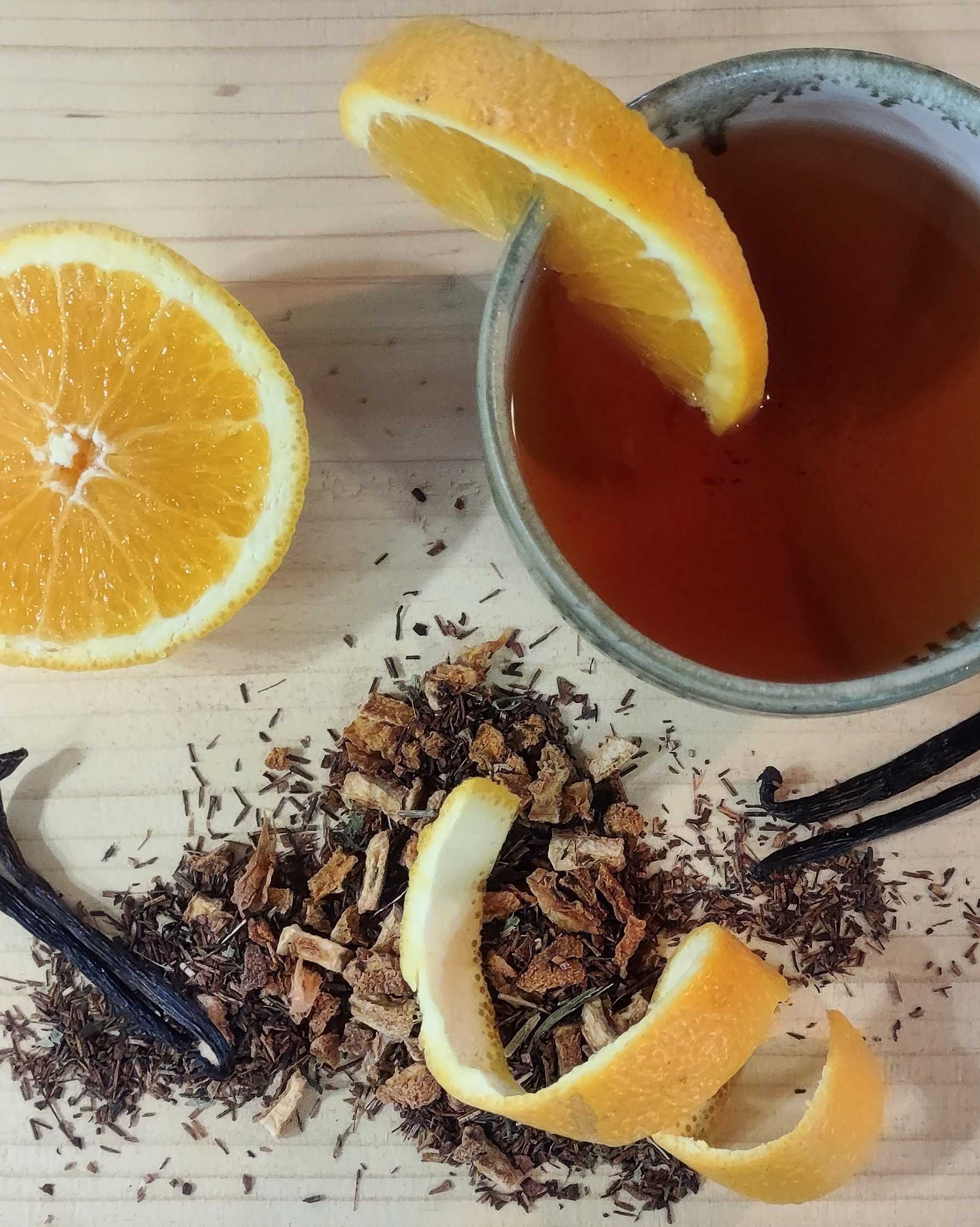 Tea with orange slices and vanilla beans on a wooden surface